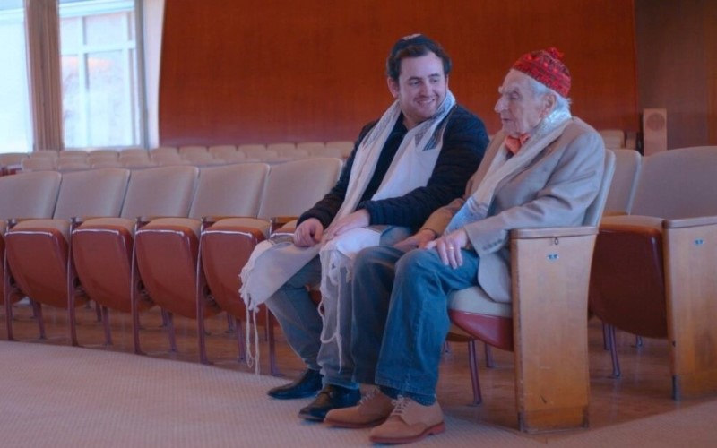 El Dr. Howard Tucker y su nieto Austin Tucker, que está haciendo un documental sobre su abuelo, hablan juntos en la sinagoga. (Cortesía de la película "¿Qué sigue?")