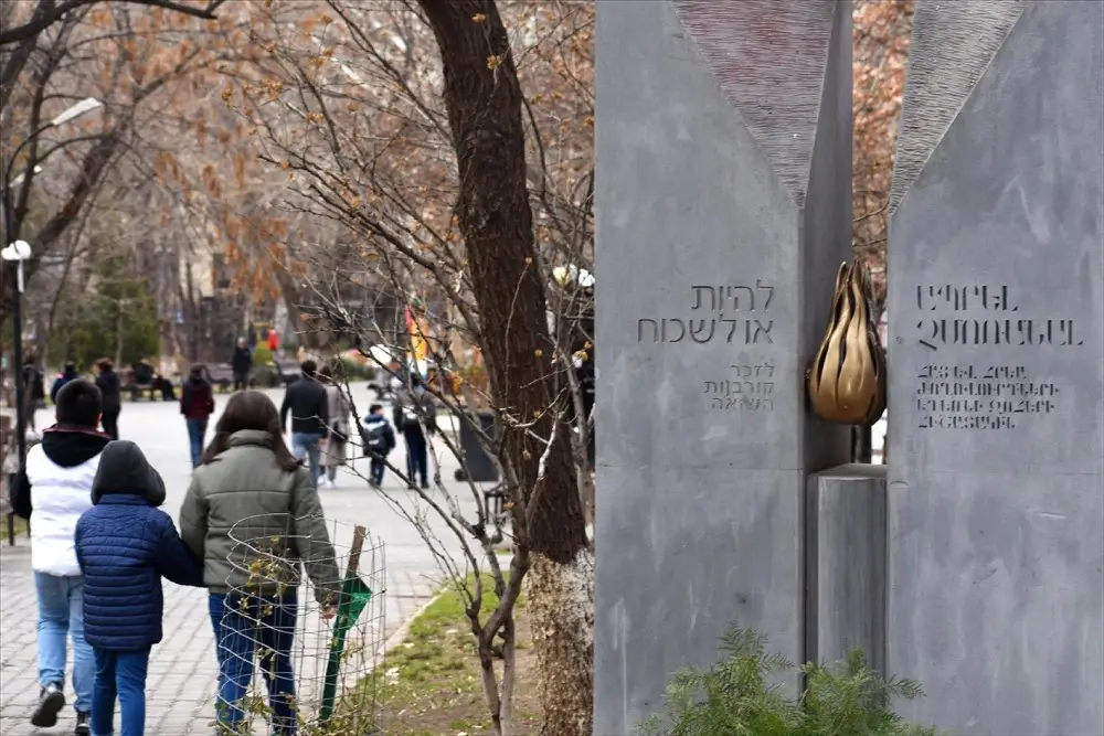 La gente pasa por el monumento al Holocausto en Ereván, que tiene una inscripción en hebreo y armenio: "Ser u olvidar: Recuerda a las víctimas del Holocausto". (Larry Luxner)
