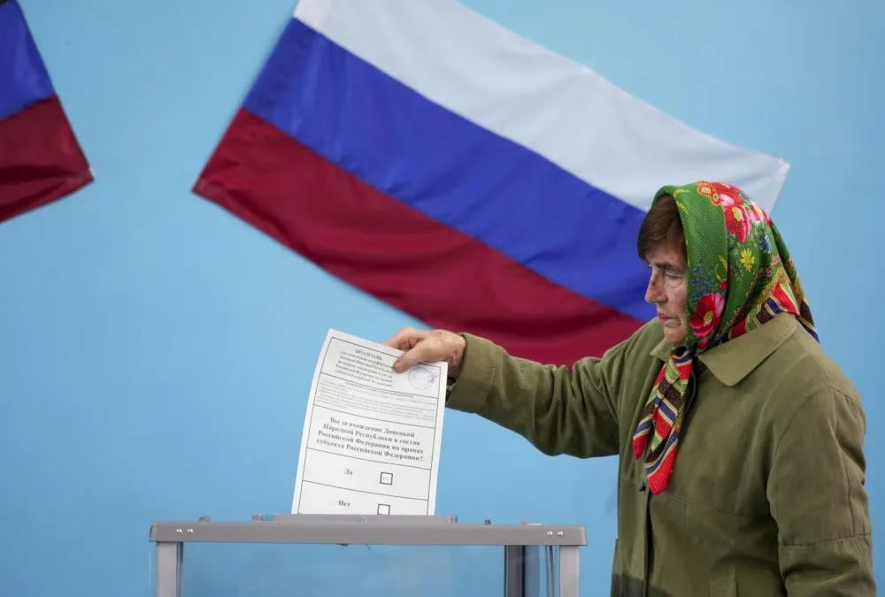 Una mujer vota "sí" sobre si su área debería formar parte de Rusia, parte de los controvertidos referéndums organizados por las fuerzas de ocupación rusas en cuatro regiones de Ucrania.