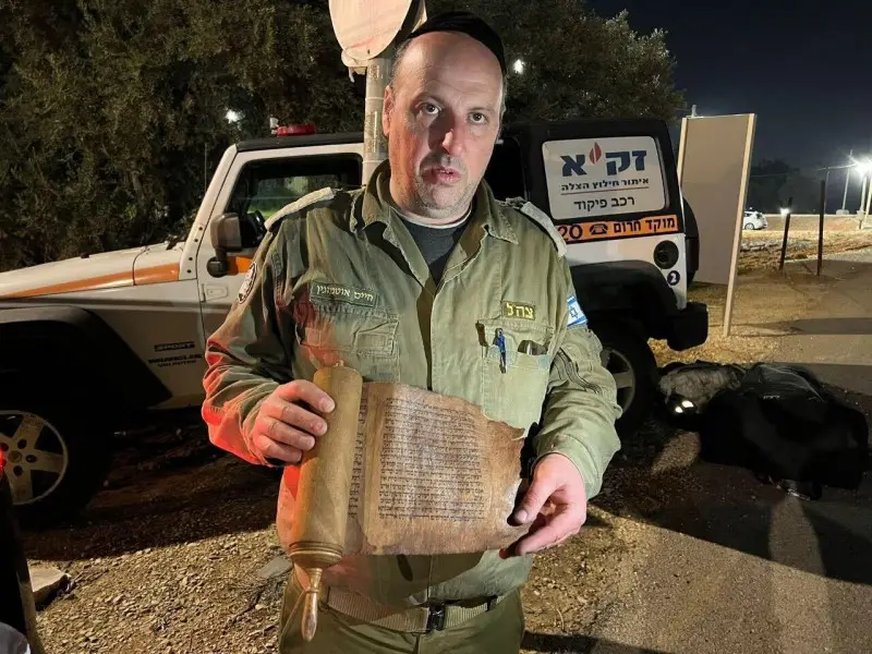 Chaim Otmazgin, voluntario de ZAKA, sostiene uno de los pergaminos traídos de Turquía a Israel el 13 de febrero de 2023.