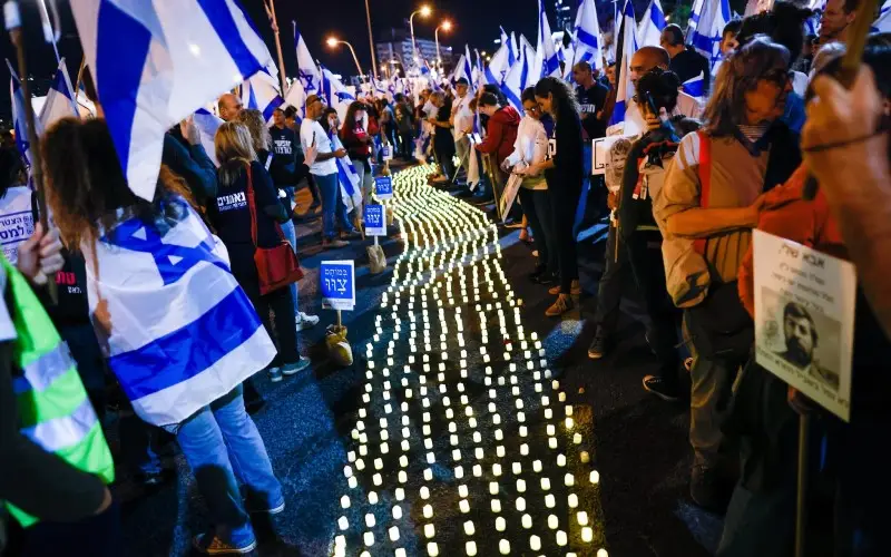 Familias en duelo e israelíes se paran junto a velas conmemorativas durante una protesta contra la revisión judicial planificada por el gobierno israelí en Tel Aviv