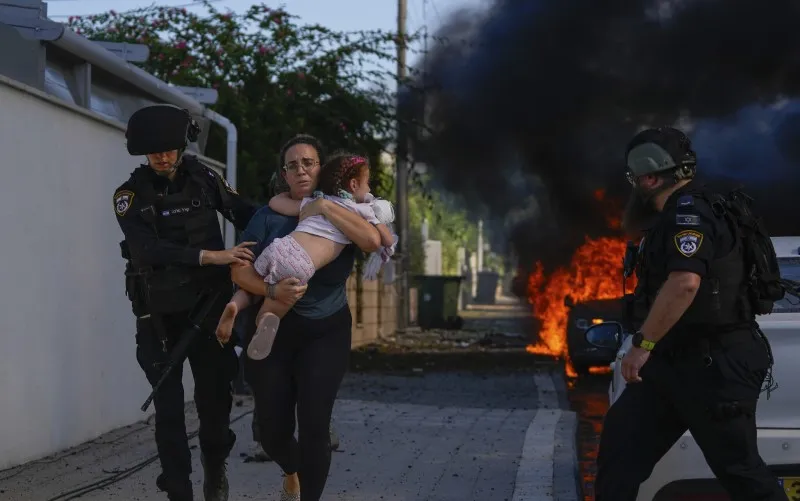 Agentes de policía evacuan a una mujer y un niño de un sitio alcanzado por un cohete disparado desde la Franja de Gaza, en Ashkelon, sur de Israel.