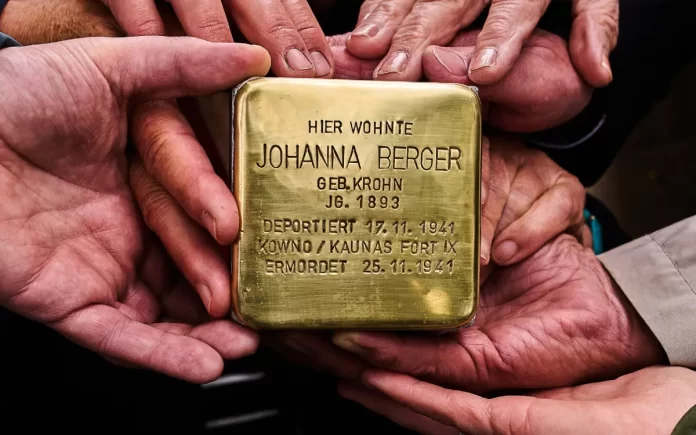 Familiares sostienen la placa conmemorativa Stolperstein de Johanna Berger frente a su antigua vivienda en Berlín, Alemania